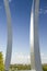 Commercial jet flies over Air Force Memorial with three soaring spires and Washington Monument in distance at One Air Force