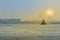 Commercial ship sailing on the river near a bridge during sunset