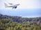 Commercial white plane airliner flying over the sea and mountains. Travel concept