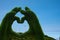 Commitment to green energy. View of wind generators against the blue sky through a green heart from the hands.