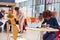 Communal Area Of Busy College Campus With  Female Student Working At Tables And Using Mobile Phone