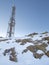 communications tower with mobile phone antennas on top of a snowy mountain, vertical