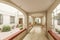 Community interior of a house with a hallway leading to a terrace full of potted plants, cream marble floors and window bars