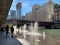 Commuters walk along a splashpad fountain on the riverwalk of the Chicago River