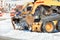 The compact and agile grader with hydraulic front blade clears snow from the city square