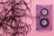 Compact audio cassette on pink background with the tangled tape
