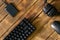 Compact black gaming computer keyboard, headphones, external ssd and computer mouse on a table made of wooden pine boards.