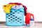 Compact concentrated laundry liquid detergent and regular liquid detergent next to basket full of apparels