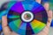 Compact Disc. Holding a CD in hands. The back side of the CD reflects colorful lights. Rainbow colors