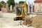 Compact excavator at work among the foundations and the pillars of a residential building