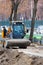 A compact grader moves along a sidewalk under construction at a construction site. Vertical image