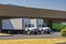 Compact medium size rigs day cab semi trucks with long box trailers for local delivery standing at warehouse dock loading