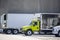 Compact middle duty day cab semi truck with refrigerated box trailer standing in warehouse dock in row with another semi trucks