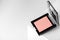 Compact pink blush on a geometric gray background close-up. Makeup beauty is a mineral product with a powdery texture. Concealer
