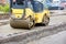 The compact road roller ramps the pavement foundation along the concrete curb and driveway