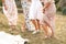 The company of female friends having fun, dancing on summerfield in long dresses showing their legs. Summer rural style picnic