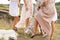 The company of female friends having fun, dancing on summerfield in long dresses showing their legs. Summer rural style picnic