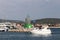 A company of friends on a small motor yacht enters the marina, sailing past a stone breakwater with a fierce signal beacon. Rest