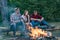 Company friends spend great time picnic or barbecue near bonfire. Picnic friends. Friends roasting hotdogs on sticks at