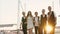 Company of friends who look like musicians stroll along the pier in the evening