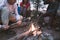 Company of happy friends fries delicious marshmallows on a bonfire, on a summer evening in the forest