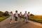 Company of happy young stylish guys walk on a country road on a sunny day