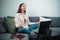 The company holds a webinar on stress relief at home, a girl sits on the couch in front of a laptop and meditates