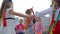 Company of little girlfriends in flower wreaths dance holding hands on street