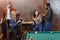 company of multiethnic friends eating and drinking beside pool table