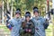 Company of three smiling paintball players posing outdoors