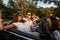 Company of young people riding in a cabriolet on the road on a warm sunny day. Two beautiful girls and a young man