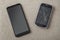 Comparison of two black mobile phones, old cellphone with cracked screen and new modern on light cloth copy space background.