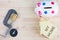 Compass, home replica, piggy bank and coins squeezed tightly in a G-Clamp over wooden background