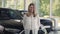 Competent female auto dealer in white shirt posing at work