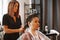 Competent female hairdresser deciding what haircut to do in hair salon with brunette female client