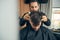 Competent young barber looking at dark hair