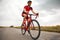 Competitive and motivated man, triathlete riding bicycle on road outdoors, training for marathon