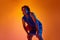 Competitive spirit. Young motivated man, athlete, basketball player standing with ball against orange background in neon