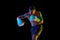 Competitive, strong, muscular young man, boxing athlete training shirtless isolated over black background in neon light