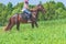Competitor rival girl riding horse in summer field meadow.Young rider gallops through the summer sunny day