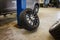 a complete wheel leans against a pillar in a car repair shop