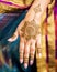Completed Mehndi design displayed on hand and fingers of Indian wedding guest.