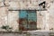Almost completely rusted blue sliding metal doors mounted on abandoned factory wall with destroyed facade surrounded with concrete