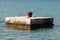 Completely rusted dilapidated iron mooring bollard in middle of stone pier surrounded with calm sea used for tying larger ships