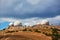 Complex building standing on hill. Dark stormy sky. Mountain in desert terrain. Technology and research station concept