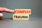 Complex trauma symbol. Concept words Complex trauma on wooden block. Beautiful grey table grey background. Doctor hand. Business