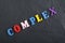 COMPLEX word on black board background composed from colorful abc alphabet block wooden letters, copy space for ad text