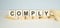 Comply word on wooden cubes on a light