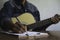 Composer holding pencil and writing lyrics in paper. Musician playing acoustic guitar