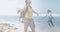 Composite of happy african american woman hiking, and dancing in sea at the beach